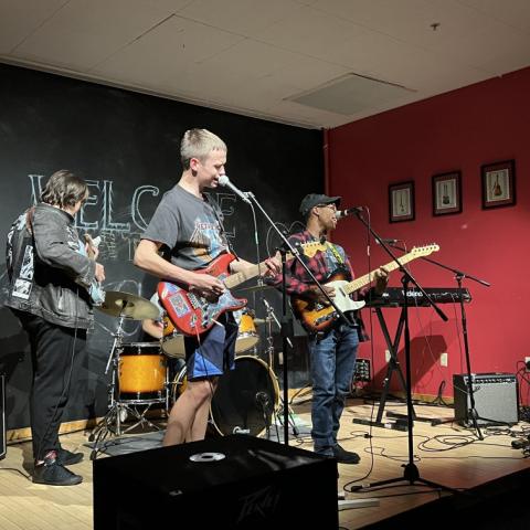 Students within the JAM Program House playing instruments on stage during an Open Mic Night event